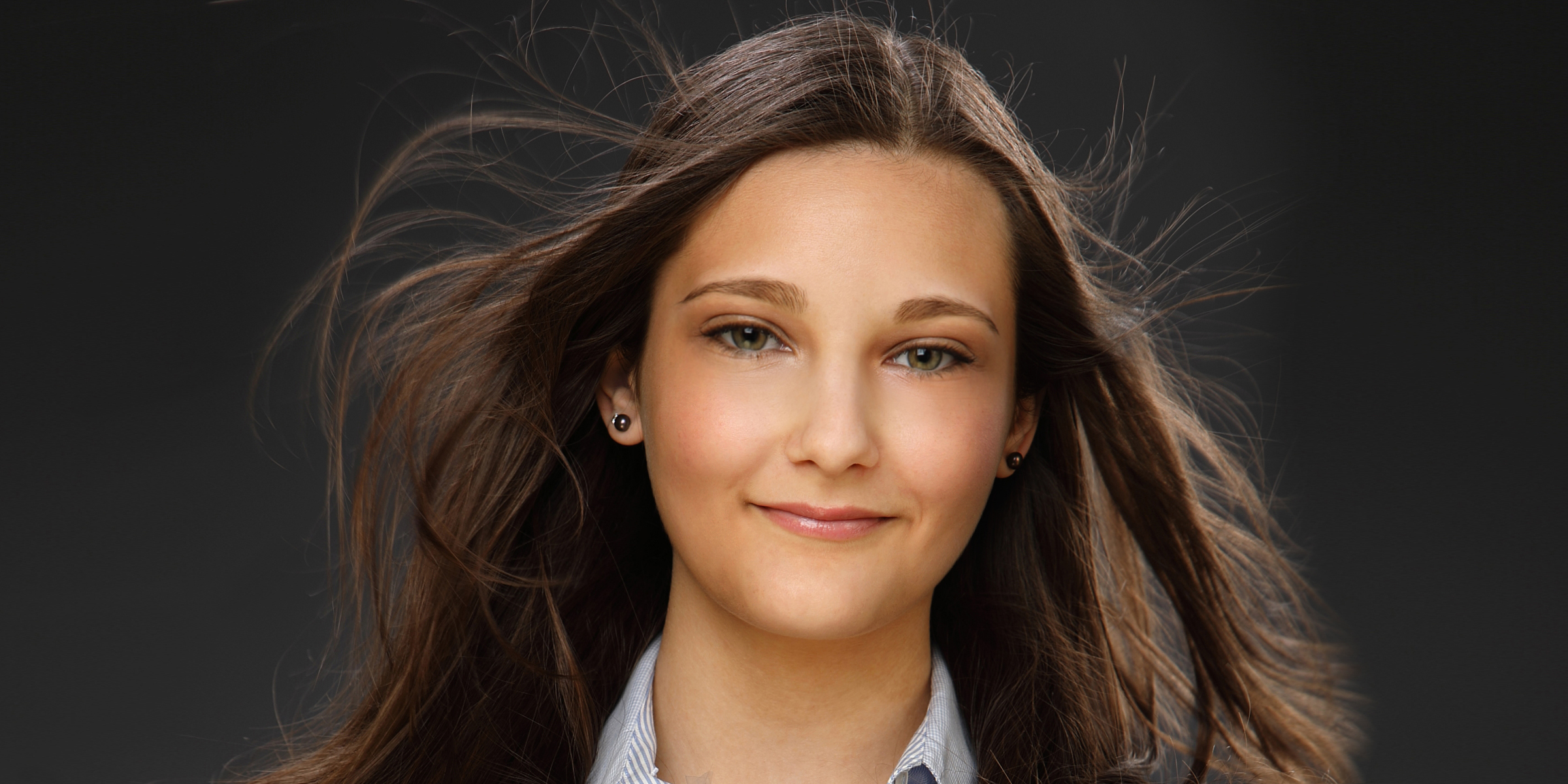 Portrait einer Frau mit fliegenden Haaren posiert glücklich für Business-Foto.